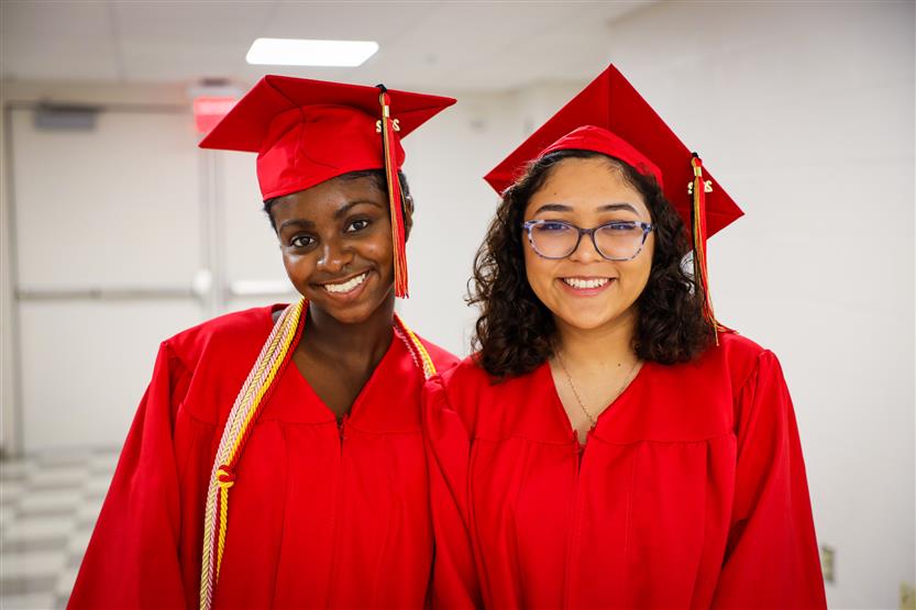 Students in red robes graduate